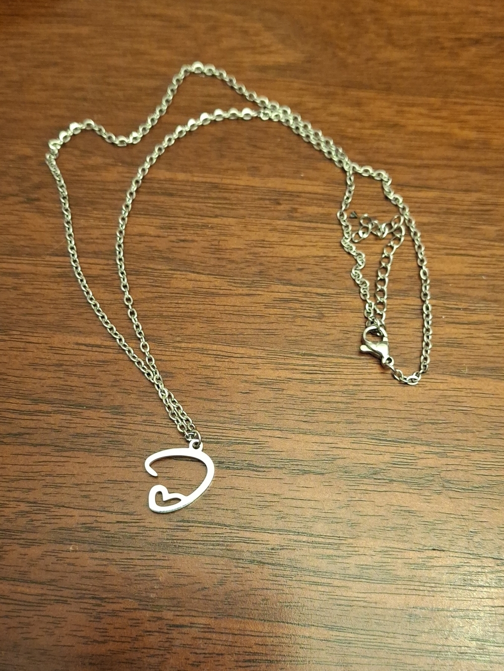Silver-toned pendant necklace  delicate curved loop protecting heart New